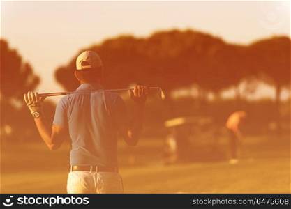 golfer from back looking to ball and hole in distance, handsome middle eastern golf player portrait from back with beautiful sunset in background. golfer from back at course looking to hole in distance