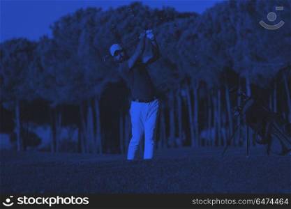 golfer hitting a sand bunker shot on sunset. golfer shot ball from sand bunker at golf course with beautiful sunset in background duo tone