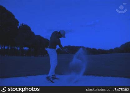 golfer hitting a sand bunker shot on sunset. golf player shot ball from sand bunker at course with beautiful sunset with sun flare duo tone