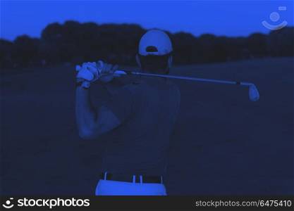golfer hitting a sand bunker shot on sunset. golf player shot ball from sand bunker at course with beautiful sunset with sun flare duo tone