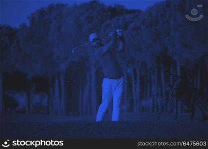 golfer hitting a sand bunker shot on sunset. golfer shot ball from sand bunker at golf course with beautiful sunset in background duo tone