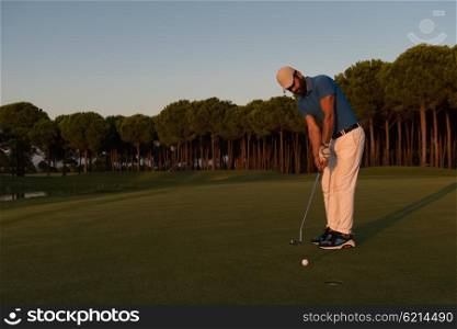 golfer hitting ball shot with driver on golf course at beautiful sunset in background