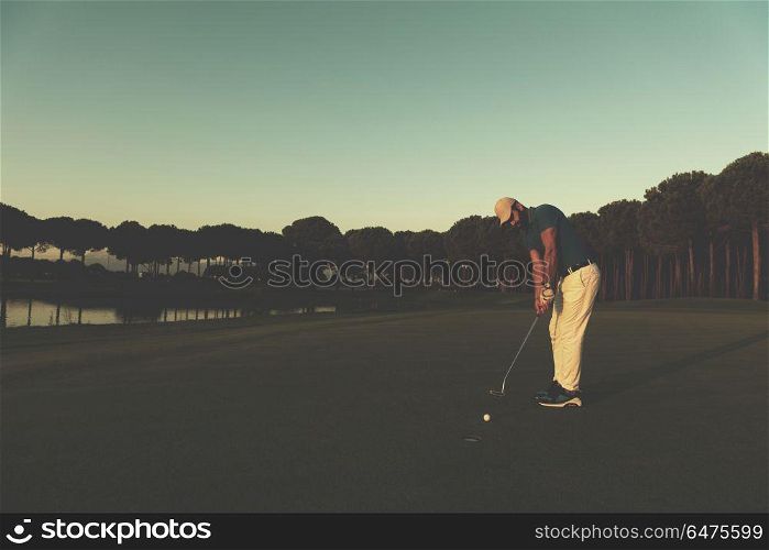 golfer hitting ball shot with driver on golf course at beautiful sunset in background. golfer hitting shot at golf course