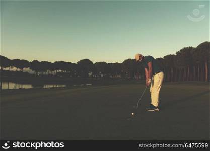 golfer hitting ball shot with driver on golf course at beautiful sunset in background. golfer hitting shot at golf course