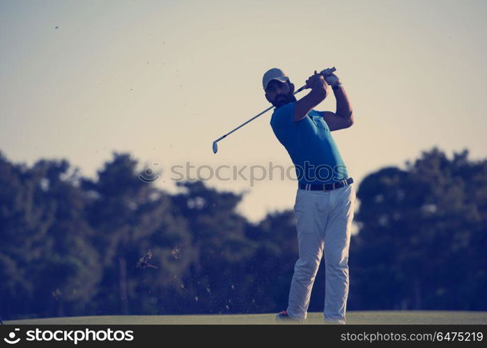 golfer hitting long shot with driver on course at beautiful sunset. golfer hitting long shot