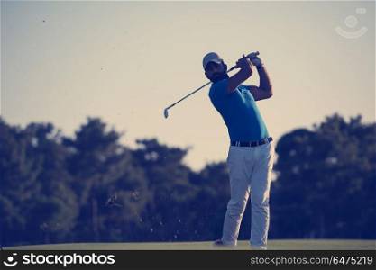 golfer hitting long shot with driver on course at beautiful sunset. golfer hitting long shot