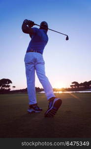 golfer hitting long shot with driver on course at beautiful sunset. golfer hitting long shot