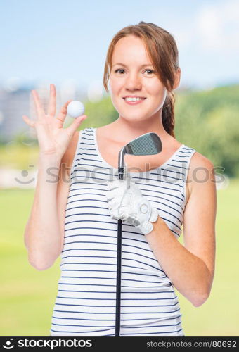 Golfer holding a golf club and showing a white ball on a background of golf courses