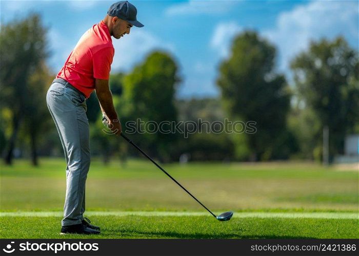 Golfer preparing to hit a golf ball, beautiful day on a golf course