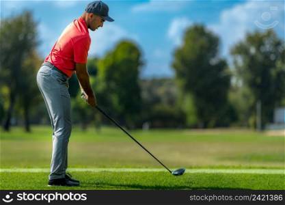 Golfer preparing to hit a golf ball, beautiful day on a golf course