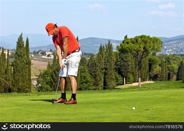 Golfer putting a ball on the green of a golf course