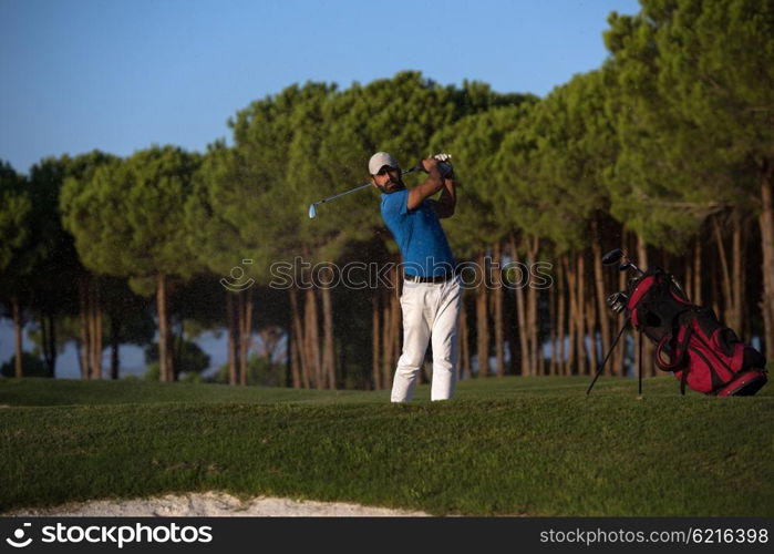 golfer shot ball from sand bunker at golf course with beautiful sunset in background