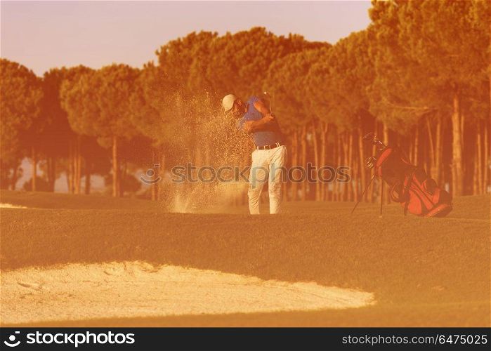 golfer shot ball from sand bunker at golf course with beautiful sunset in background. golfer hitting a sand bunker shot on sunset