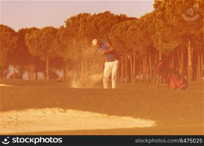 golfer shot ball from sand bunker at golf course with beautiful sunset in background. golfer hitting a sand bunker shot on sunset