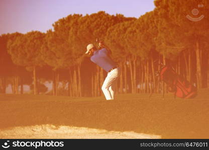 golfer shot ball from sand bunker at golf course with beautiful sunset in background. golfer hitting a sand bunker shot on sunset