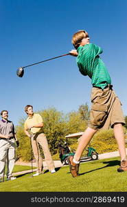 Golfer Teeing Off While Friends Watch