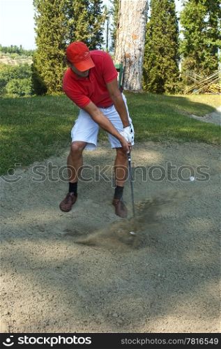 Golfer, using a sand wedge to get his ball out of a sand trap on a golf course