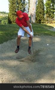 Golfer, using a sand wedge to get his ball out of a sand trap on a golf course