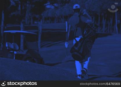 golfer walking and carrying golf bag. handsome middle eastern golfer carrying bag and walking to next hole at golf course duo tone