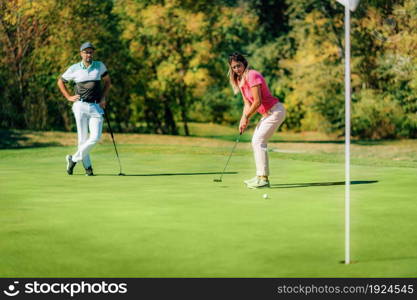 Golfing couple, putting on the green, beautiful weather. Golfing couple, putting on the gren, beautiful weather