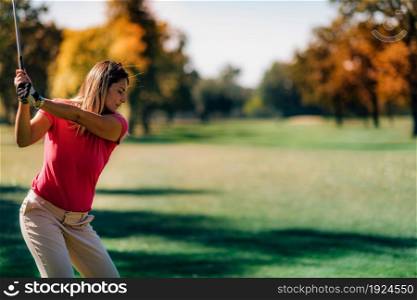 Golfing lady in a golf swing, shot from behind