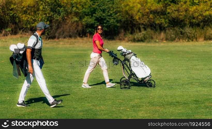 Golfing lifestyle couple walking on the golf course, enjoying a beautiful autumn day