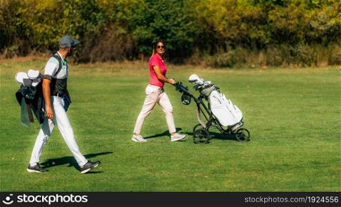 Golfing lifestyle couple walking on the golf course, enjoying a beautiful autumn day