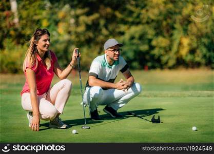 Golfing lifestyle. Golf couple on the putting green, enjoing the beautiful sunny day