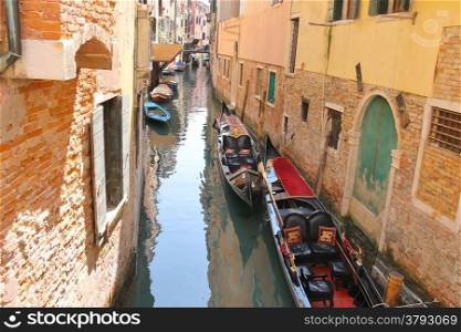 Gondolas and boats in a narrow canal in Venice, Italy