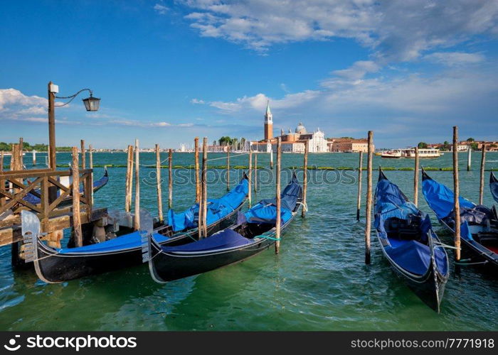 Gondolas and in lagoon of Venice by Saint Mark  San Marco  square with San Giorgio di Maggiore church in background in Venice, Italy. Gondolas and in lagoon of Venice by San Marco square. Venice, Italy