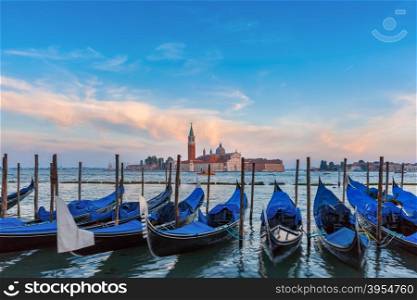 Gondolas moored by Saint Mark square with San Giorgio di Maggiore church in the background in the evening, Venice, Italia