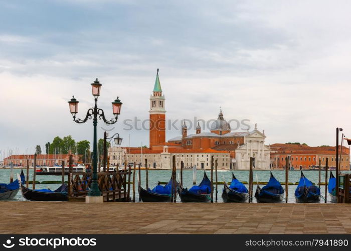 Gondolas moored by Saint Mark square with San Giorgio di Maggiore church in the background at twilight in Venice lagoon, Italia