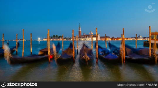 Gondolas moving water in the lagoon of Venice in front of San Giorgio island.