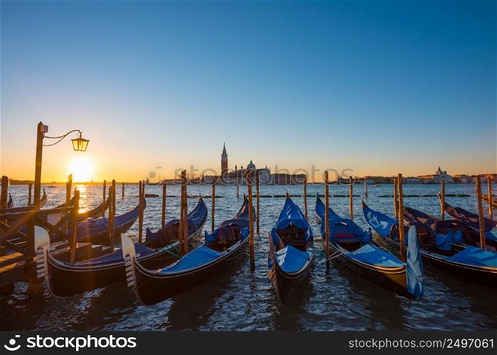 Gondolas. Venice Italy seafront with gondolas and church on background at sunrise.