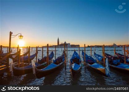 Gondolas. Venice Italy seafront with gondolas and church on background at sunrise.