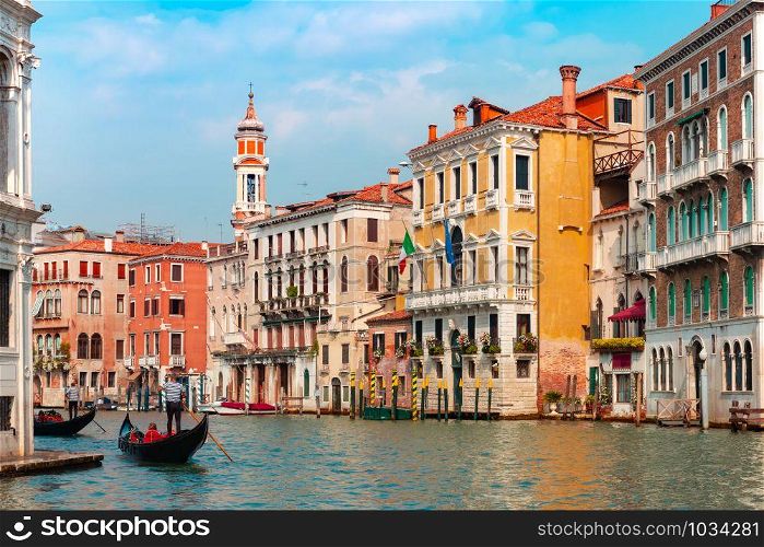 Gondolier carries tourists on Traditional gondola along Grand Canal in summer sunny day, Venice, Italy. Grand canal in summer sunny day, Venice, Italy