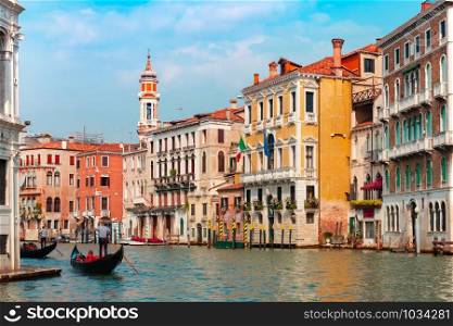 Gondolier carries tourists on Traditional gondola along Grand Canal in summer sunny day, Venice, Italy. Grand canal in summer sunny day, Venice, Italy