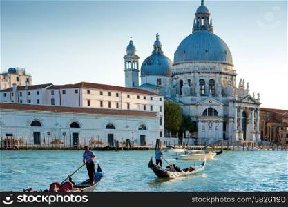 Gondoliers on gondola at Grand Canal in Venice. Basilica Santa Maria della Salute in sunny day