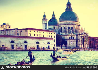 Gondoliers on gondola at Grand Canal in Venice. Basilica Santa Maria della Salute in sunny day. Instagram like filter
