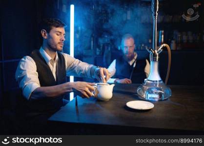 Good friends meeting in hookah lounge. Two guys smoking shisha and drinking tea in cafe or bar. Relax concept. Good friends meeting in hookah lounge, relax concept