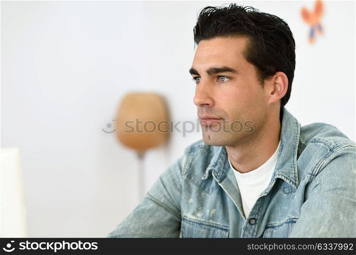 Good looking man wearing denim shirt sitting in a coffee bar. Blue eyes guy with casual clothes.