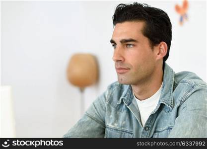 Good looking man wearing denim shirt sitting in a coffee bar. Blue eyes guy with casual clothes.