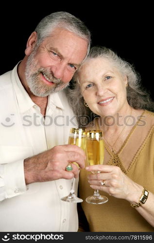 Good looking mature couple toasting the season with champagne. Black background.