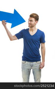 Good looking young man holding a blue arrow, isolated on a white background