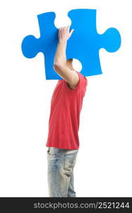 Good looking young man holding a blue puzzle piece, isolated on a white background