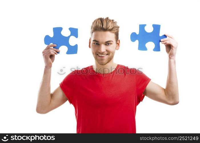 Good looking young man holding a blue puzzle piece, isolated on a white background
