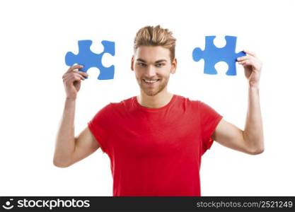 Good looking young man holding a blue puzzle piece, isolated on a white background