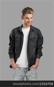 Good looking young man smiling with hands in the pockets, isolated over a gray background