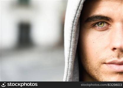Good looking young man with blue eyes in the street wearing hooded jacket