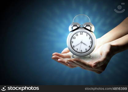 Good morning. Close up image of human palms with alarm clock